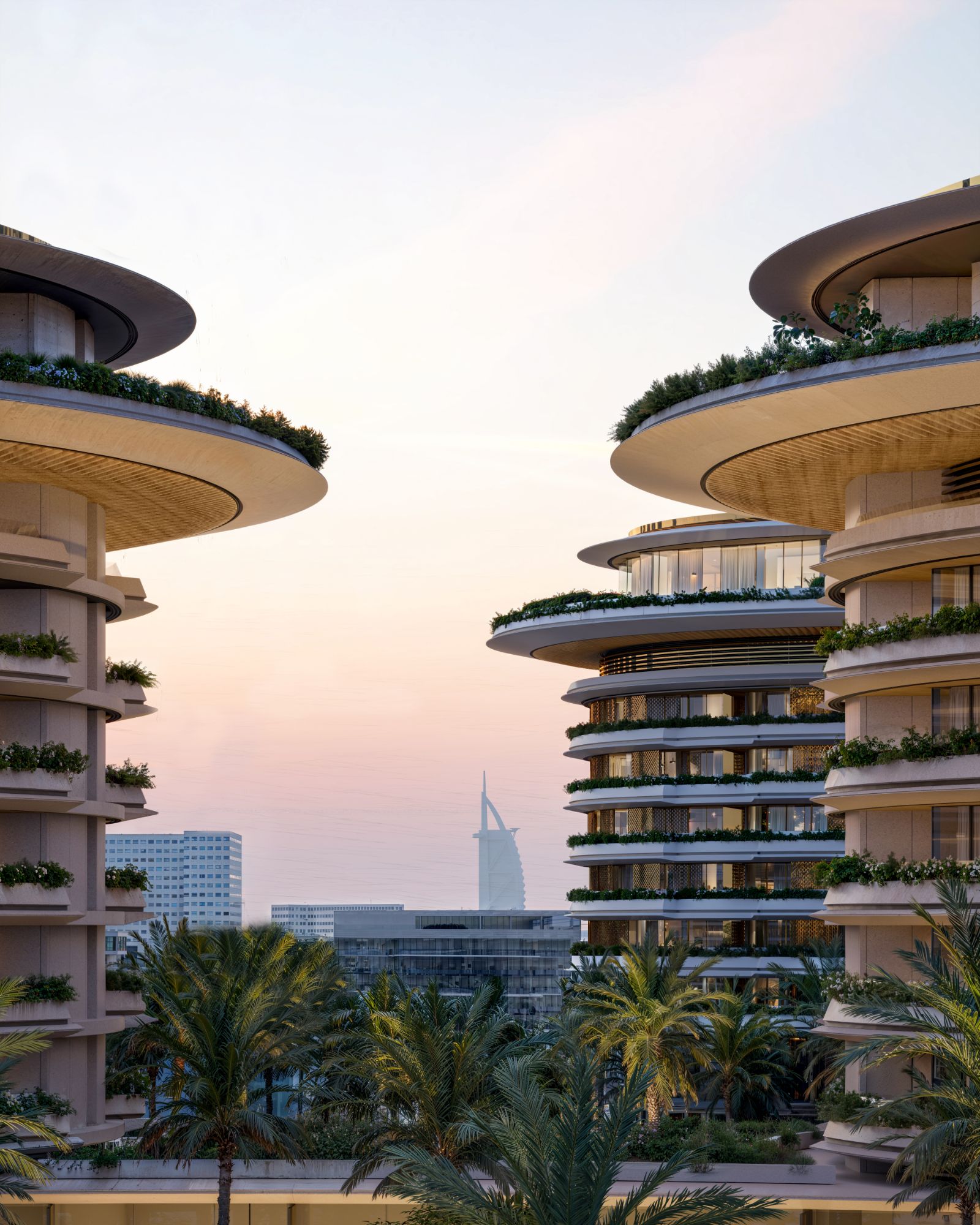 Torri residenziali con terrazze verdi e il Burj Al Arab sullo sfondo al tramonto